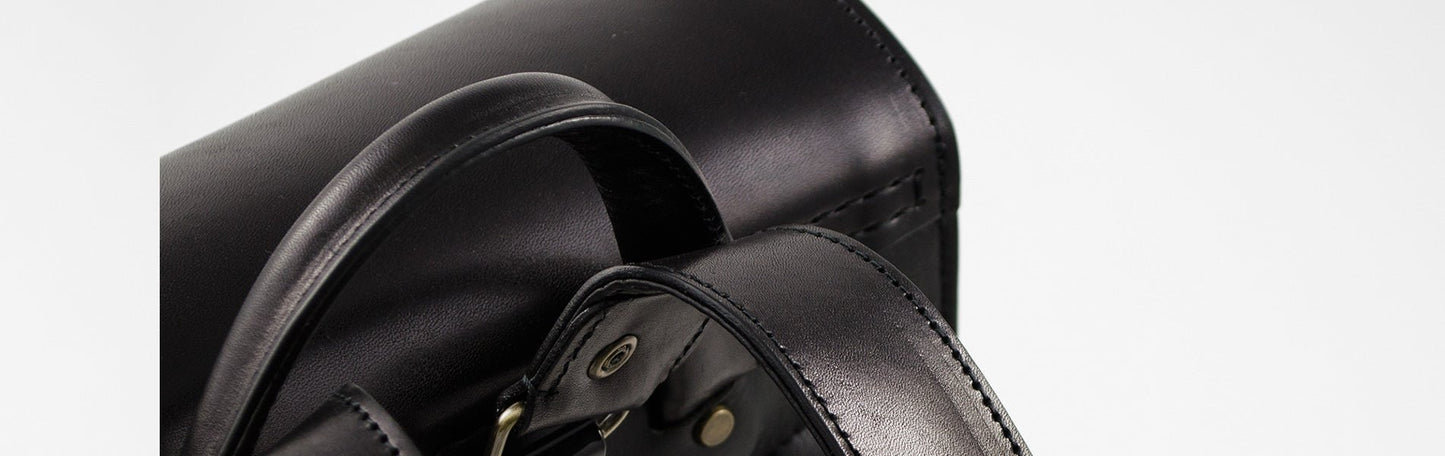 Close-up of a black leather bag with visible stitching on a white background