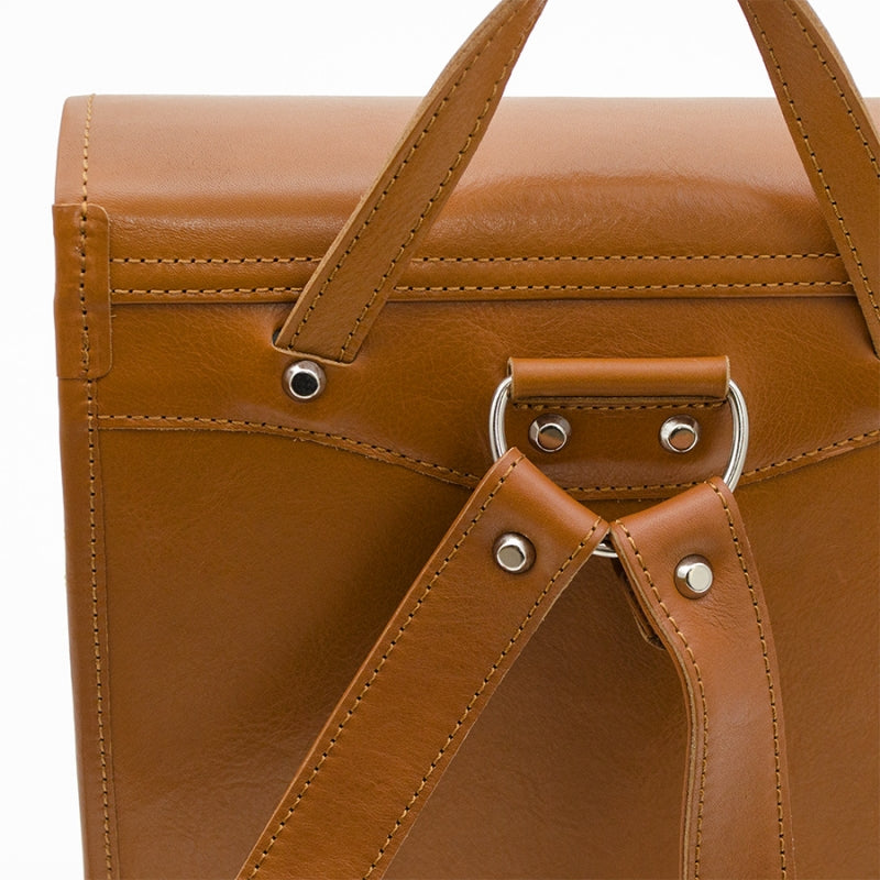 Close-up of a brown leather bag with handle and strap on a white background