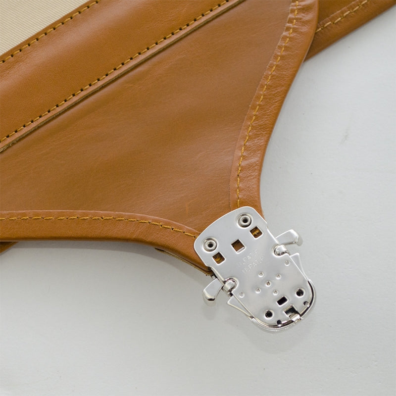 Close-up of a brown leather product with a silver metal clip on a light gray background