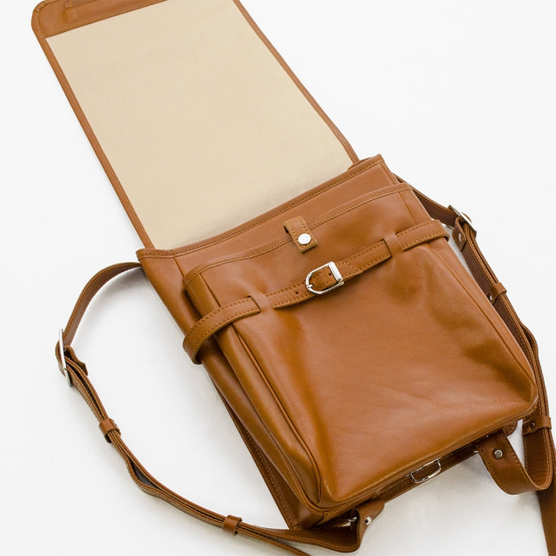 Brown leather bag with a strap on a white background