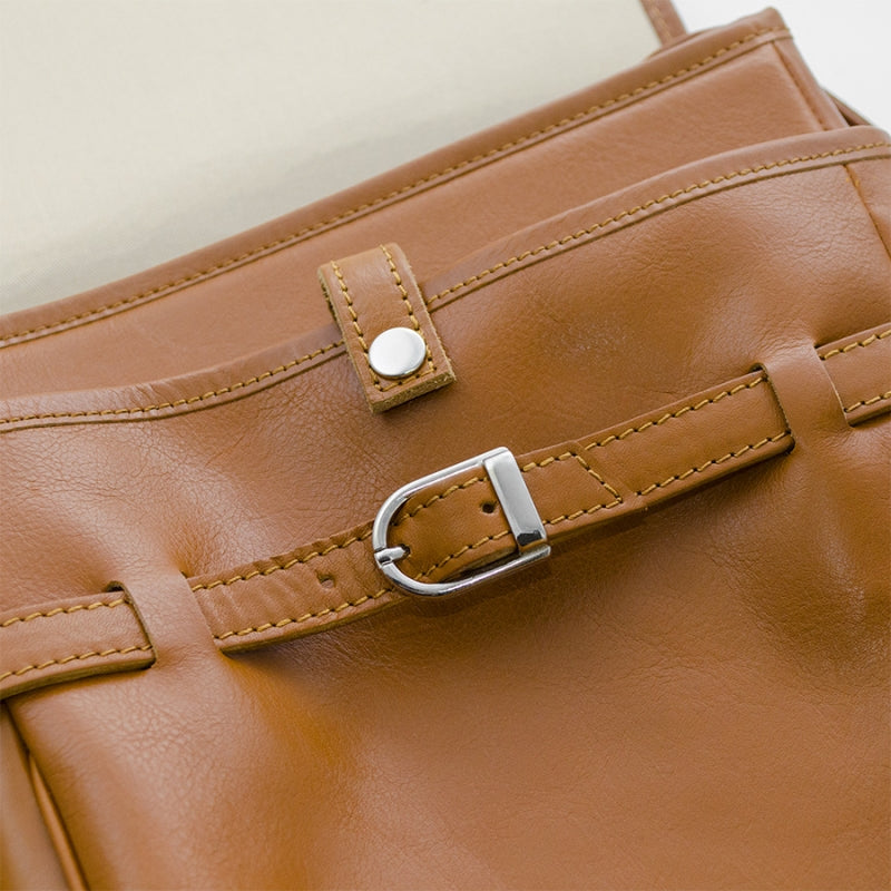 Close-up of a brown leather bag with a buckle detail.