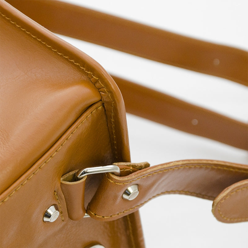Close-up of a brown leather bag with a strap on a white background