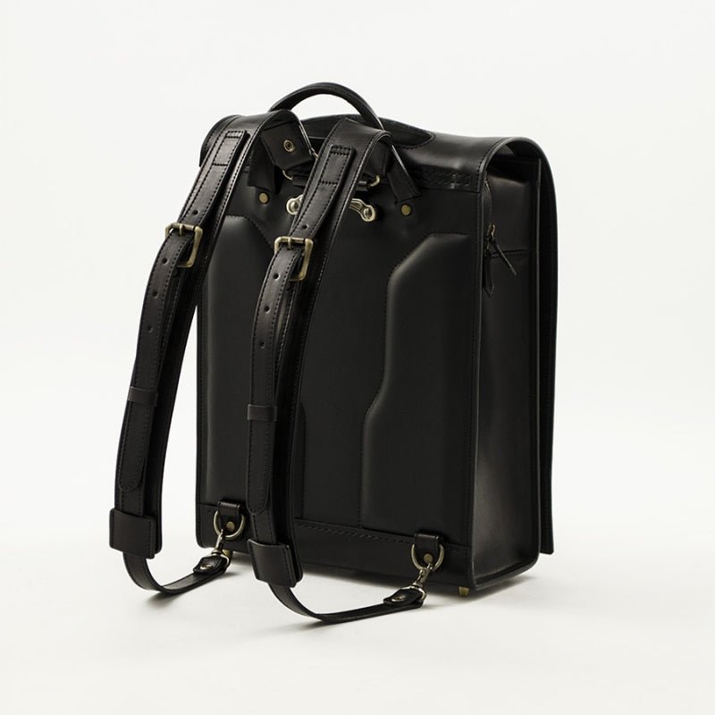 Black leather backpack with gold hardware on a white background