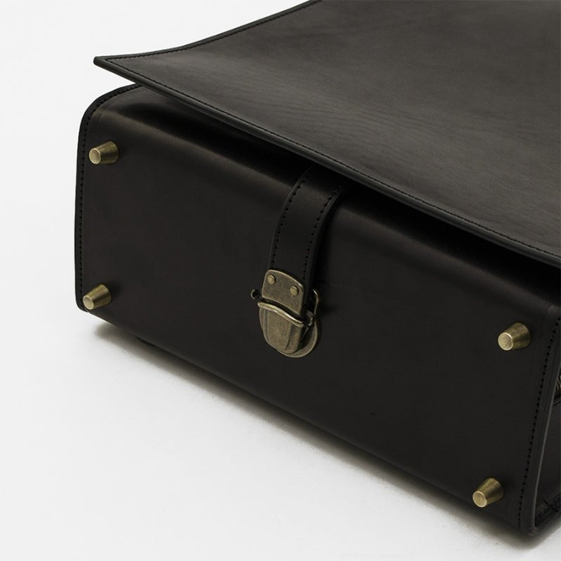 Black leather bag with gold hardware on a white background