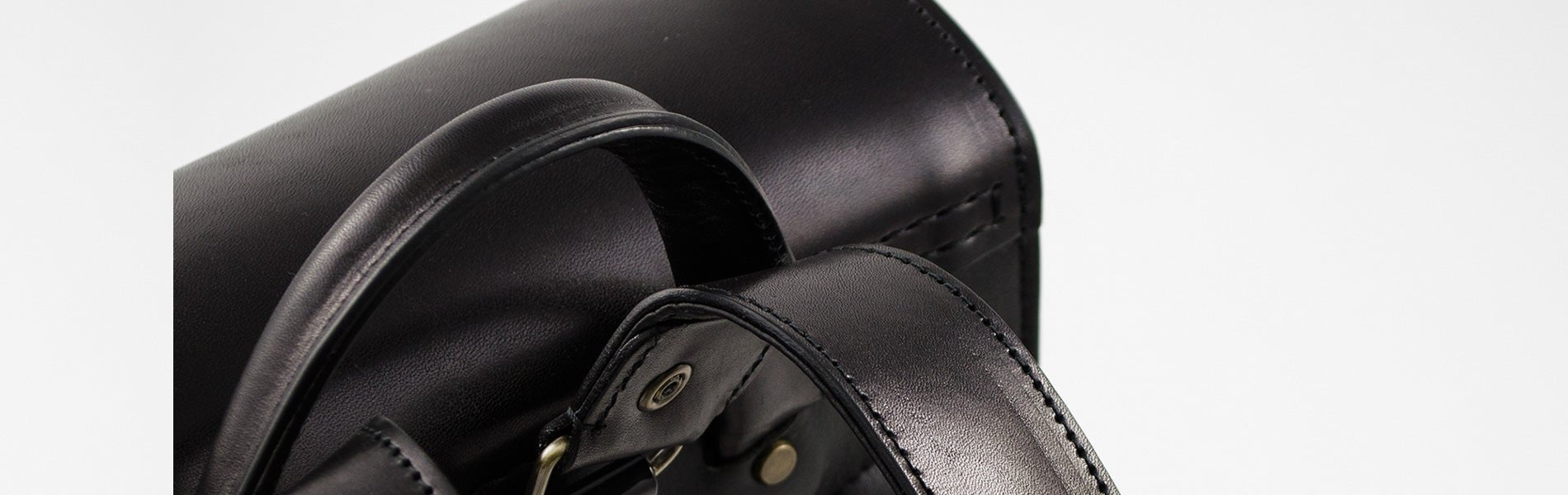 Close-up of a black leather bag with visible stitching on a white background